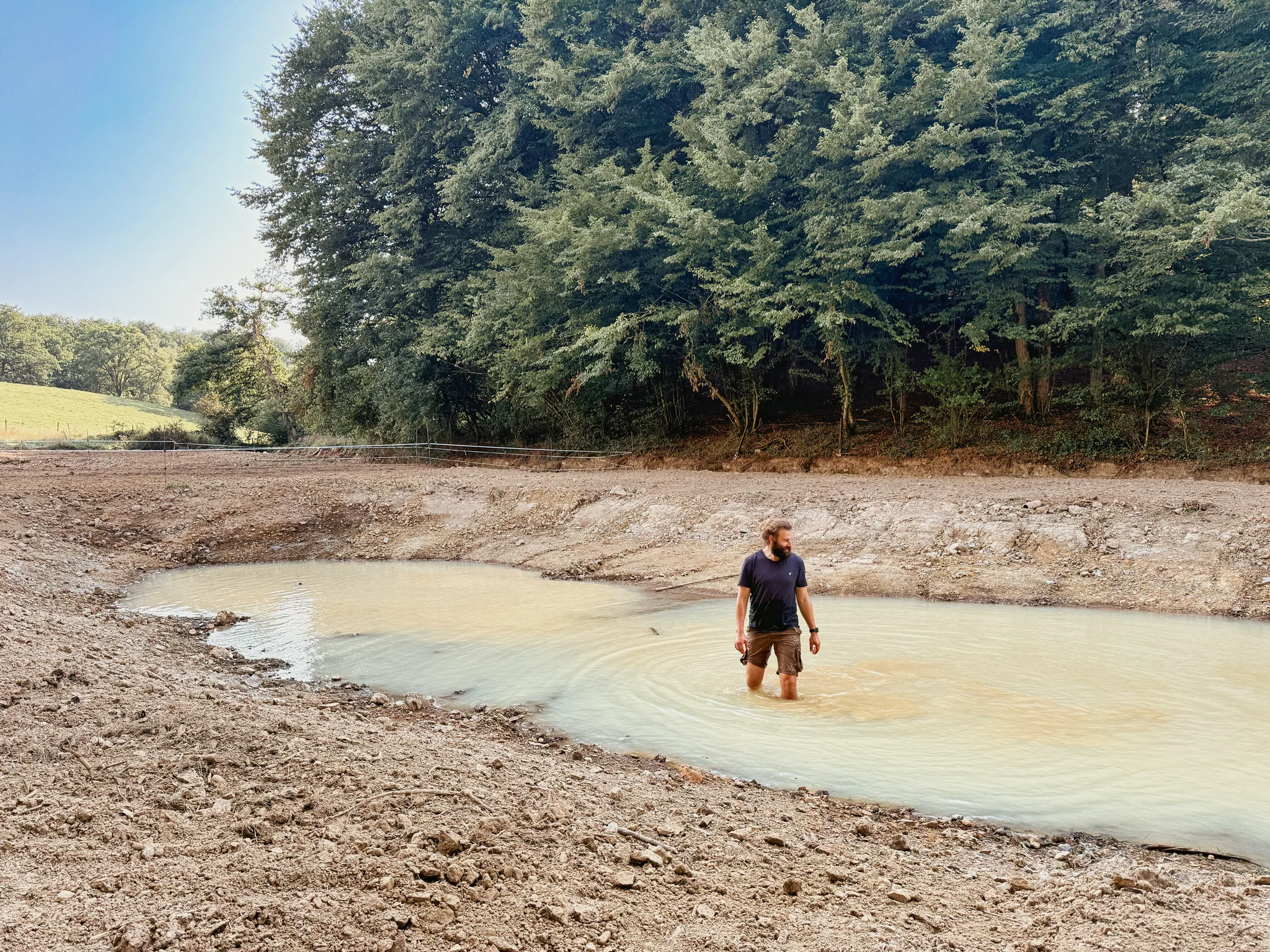 Louis debout dans l’eau d’une mare récemment creusée